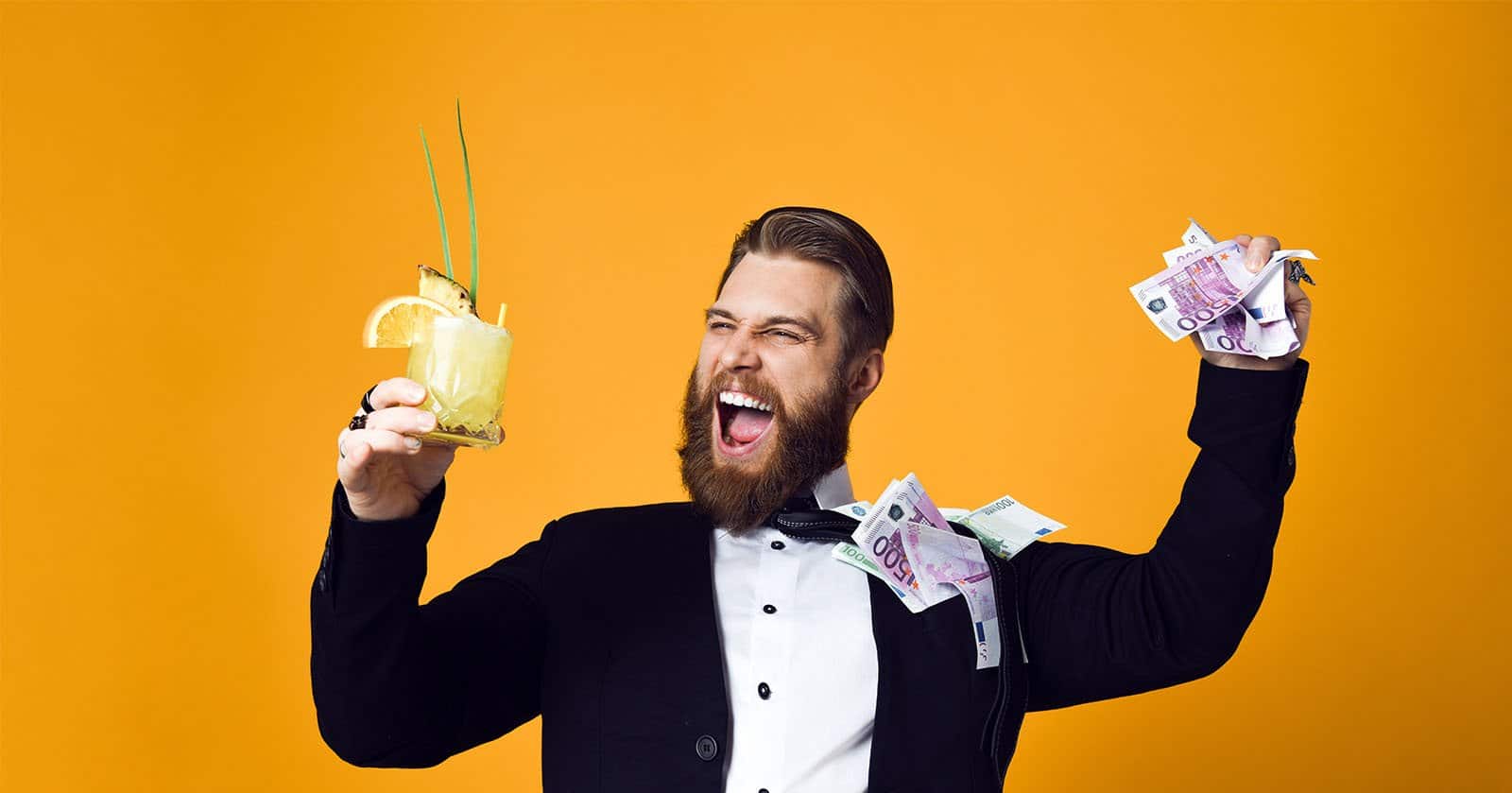 freudiger Mann mit Geld und Cocktail in der Hand